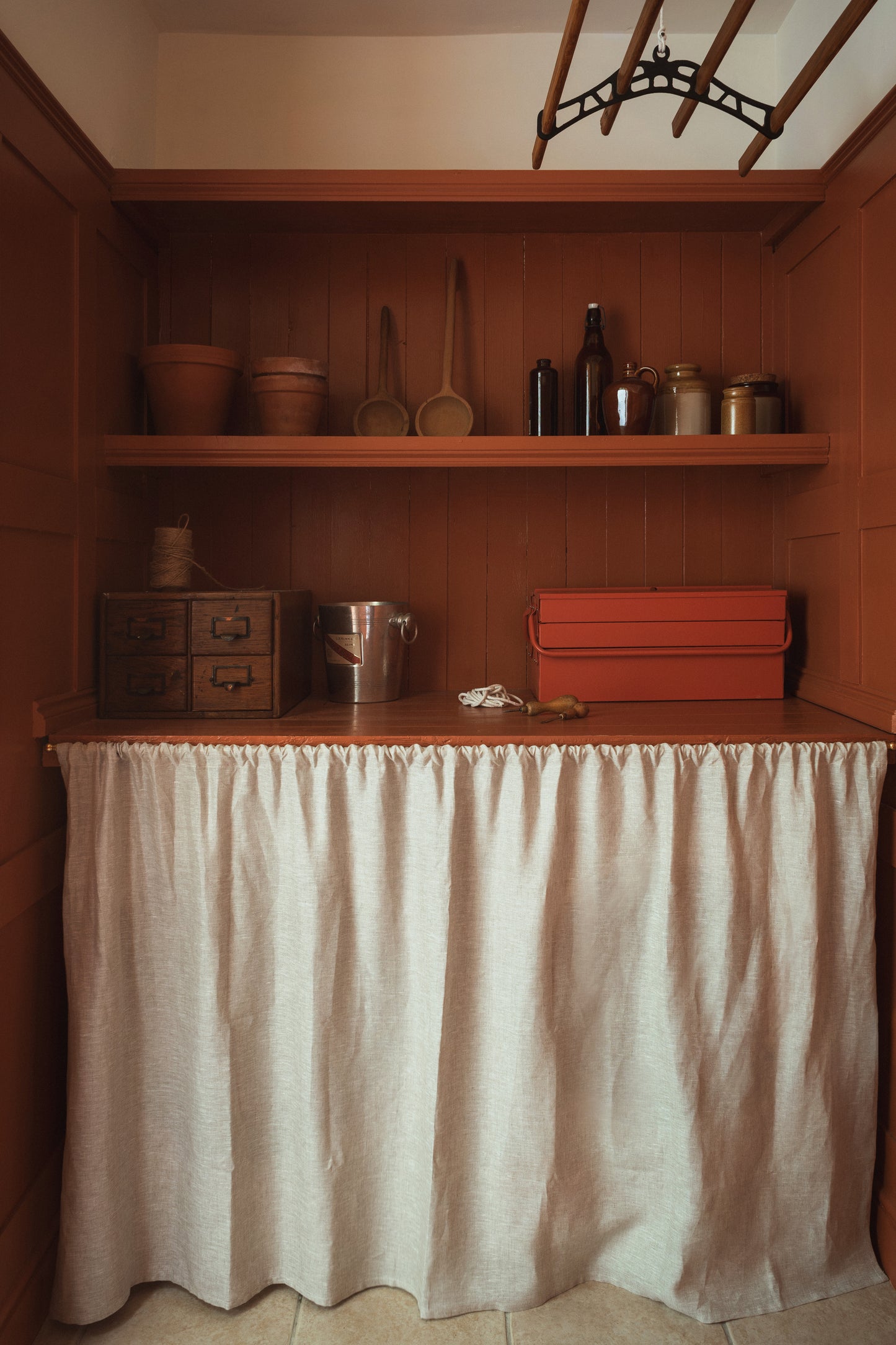 Wooden shelves with various items in a room with a white curtain.